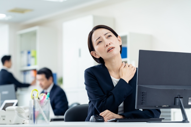 オフィスで肩こりで疲れた女性